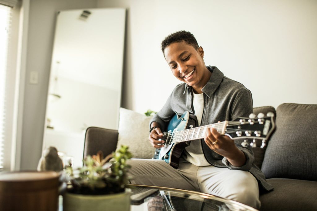 Woman playing electric guitar in living room